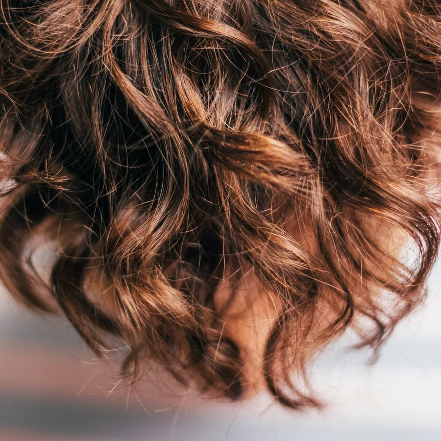 Close de cabelo ondulado castanho com brilho natural